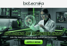 Exciting Life Science Job at Monster Energy | Don’t Miss This Opportunity Exciting Life Science Job at Monster Energy Don't Miss This. A job advertisement image with the header logo "biotecnika Your Bio Resource" and a stylized figure. The central scene is a detailed, futuristic laboratory with green lighting, where a female scientist in a lab coat interacts with a glowing hologram of an ATP molecule and "Human Performance Cell." Background monitors display biometric data and a separate room shows gamers and a person on a treadmill, symbolizing human performance research. Large bold text across the middle reads "LIFE SCIENCE JOB AT MONSTER ENERGY", followed by the subtext, "Join the team powering peak human performance." A prominent green "APPLY NOW" button is at the bottom center.