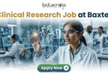 Latest Clinical Research Job for Life Science & Biomedical Graduates at Baxter | Apply Now Latest Clinical Research Job at Baxter | Apply Now. A featured job advertisement banner for biotecnika, titled "Clinical Research Job at Baxter," set in a modern, futuristic laboratory. The visual focuses on a diverse female scientist, of South Asian or Indian descent, with safety glasses and a lab coat, who is interacting with and gesturing towards a floating, transparent holographic screen. The screen displays complex 3D molecular models of a protein and a drug, along with labels like 'Protein Drug Docking' and 'Data Docking'. In the blurred background, other researchers work with equipment and computer monitors in a well-equipped facility. At the top center is the "biotecnika Your Bio Resource" logo. At the bottom center, a prominent green button contains the text 'Apply Now' with a white arrow icon.