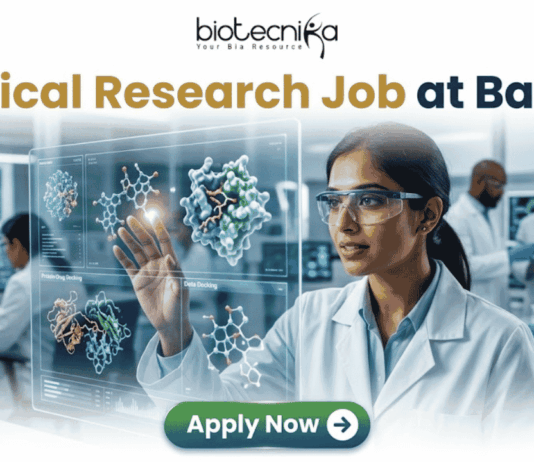 Latest Clinical Research Job for Life Science & Biomedical Graduates at Baxter | Apply Now Latest Clinical Research Job at Baxter | Apply Now. A featured job advertisement banner for biotecnika, titled "Clinical Research Job at Baxter," set in a modern, futuristic laboratory. The visual focuses on a diverse female scientist, of South Asian or Indian descent, with safety glasses and a lab coat, who is interacting with and gesturing towards a floating, transparent holographic screen. The screen displays complex 3D molecular models of a protein and a drug, along with labels like 'Protein Drug Docking' and 'Data Docking'. In the blurred background, other researchers work with equipment and computer monitors in a well-equipped facility. At the top center is the "biotecnika Your Bio Resource" logo. At the bottom center, a prominent green button contains the text 'Apply Now' with a white arrow icon.