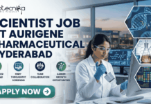 Scientist Job in Hyderabad for MSc Graduates | Aurigene Pharmaceutical Hiring Now Scientist Job for MSc Graduates at Aurigene Pharmaceutical. A professional corporate recruitment banner for a "SCIENTIST JOB AT AURIGENE PHARMACEUTICAL HYDERABAD" by Biotecnika. The image features a focused female scientist of Indian heritage in a lab coat and safety glasses, working with a multichannel pipette in a state-of-the-art pharmaceutical laboratory. The background shows a modern research facility with large windows overlooking a city skyline at dusk. Hexagonal frames to the right showcase a DNA helix, chemical glassware, and data analytics. Below the main headline, four icons highlight key aspects: Advanced Drug R&D, High-Throughput Screening, Team Collaboration, and Career Growth Opportunities. A prominent teal "APPLY NOW" button is positioned at the bottom left.