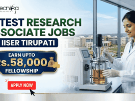 Latest Research Associate Jobs at IISER Tirupati | Earn Upto Rs.58,000 Fellowship. A professional recruitment banner for "Latest Research Associate Jobs at IISER Tirupati," featuring the Biotecnika logo at the top left. On the right, a female scientist in a white lab coat and gloves is shown working with a laboratory bioreactor in a bright, modern lab setting. The background through a large window offers a realistic view of the IISER Tirupati campus. The left side of the image features the bold headline "LATEST RESEARCH ASSOCIATE JOBS AT IISER TIRUPATI." Below this, a prominent gold-framed blue box highlights the fellowship: "EARN UPTO Rs. 58,000 FELLOWSHIP" accompanied by an icon of a money bag. Three circular icons highlight key benefits: Conduct Advanced Bio-Research, Collaboration & Mentorship, and Career Growth Path. A large green "Apply Now" button with a white arrow and the website "biotecnika.org" are positioned at the bottom.