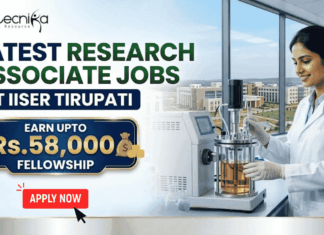 Latest Research Associate Jobs at IISER Tirupati | Earn Upto Rs.58,000 Fellowship Latest Research Associate Jobs at IISER Tirupati | Earn Upto Rs.58,000 Fellowship. A professional recruitment banner for "Latest Research Associate Jobs at IISER Tirupati," featuring the Biotecnika logo at the top left. On the right, a female scientist in a white lab coat and gloves is shown working with a laboratory bioreactor in a bright, modern lab setting. The background through a large window offers a realistic view of the IISER Tirupati campus. The left side of the image features the bold headline "LATEST RESEARCH ASSOCIATE JOBS AT IISER TIRUPATI." Below this, a prominent gold-framed blue box highlights the fellowship: "EARN UPTO Rs. 58,000 FELLOWSHIP" accompanied by an icon of a money bag. Three circular icons highlight key benefits: Conduct Advanced Bio-Research, Collaboration & Mentorship, and Career Growth Path. A large green "Apply Now" button with a white arrow and the website "biotecnika.org" are positioned at the bottom.
