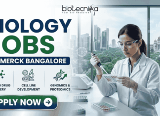 Biology Jobs at Merck in Bangalore | Apply Before It’s Gone Biology Jobs at Merck in Bangalore | Apply Before It's Gone. A Biotecnika recruitment banner advertising 'Biology Jobs' at 'Merck Bangalore.' On the right, a detailed photograph of a female scientist in a lab coat, safety glasses, and gloves meticulousy pipetting into a multi-well plate in a modern laboratory. The window behind her reveals a modern cityscape (Bangalore). The main text 'BIOLOGY JOBS' is stacked in large green and blue fonts, with 'AT MERCK BANGALORE' in a blue bar below it. Below the text, three circular icons with descriptive text list focus areas: 'ADVANCED DRUG DISCOVERY,' 'CELL LINE DEVELOPMENT,' and 'GENOMICS & PROTEOMICS.' The Biotecnika logo is in the top corner, and a prominent green 'APPLY NOW' button with a right arrow is at the bottom-left.