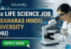 BSc Life Science Job at Banaras Hindu University | Golden Opportunity for Life Science Graduates BSc Life Science Job at Banaras Hindu University | Apply Now. A professional featured image for a "BSc LIFE SCIENCE JOB at BANARAS HINDU UNIVERSITY (BHU)." The image depicts a female scientist in a white lab coat and safety goggles using a microscope and pipette in a modern laboratory. The Biotecnika logo is at the top center, and a bright green "APPLY NOW" button with a cursor icon is at the bottom left. The background features scientific data on monitors, laboratory glassware with colorful liquids, and a DNA helix graphic.