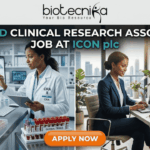 Hybrid Clinical Research Associate Job at ICON plc Apply Now. A job advertisement banner with the top text "biotecnika - Your Bio Resource" and main headline "HYBRID CLINICAL RESEARCH ASSOCIATE JOB AT ICON plc". The image uses a split-screen composition to visualize the hybrid role. The left side depicts a female Clinical Research Associate (CRA) in a lab coat in a modern research lab, analyzing data on a desktop monitor next to a microscope and a rack of marked "GLOBAL TRIALS" blood vials. The right side shows the same professional in business attire in a stylish home office with a city view, seated at a desk on a video conference call on her laptop. An orange "APPLY NOW" button is at the bottom center.