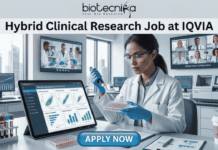 Hybrid Clinical Research Job at IQVIA | Opening for Life Science Graduates! Hybrid Clinical Research Job at IQVIA Opening for Life Science Graduates! A promotional graphic titled "Hybrid Clinical Research Job at IQVIA" at the top center, just below the biotecnika logo. The central image is a female researcher in a lab coat, nitrile gloves, and safety glasses, focused on carefully using a pipette on a multi-well plate. To her left is a large tablet displaying various clinical research charts and data plots. To her right is a paper titled "Remote Connection" and a coffee cup with a sleeve that reads "flex work". Large screens in the background show other scientists collaborating and a multi-person video conference call with a diverse team under the title "Global Team Collaboration". A centrifuge and other lab equipment are visible in the background. A prominent blue button at the bottom center reads "APPLY NOW".