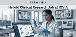 Hybrid Clinical Research Job at IQVIA | Opening for Life Science Graduates! Hybrid Clinical Research Job at IQVIA Opening for Life Science Graduates! A promotional graphic titled "Hybrid Clinical Research Job at IQVIA" at the top center, just below the biotecnika logo. The central image is a female researcher in a lab coat, nitrile gloves, and safety glasses, focused on carefully using a pipette on a multi-well plate. To her left is a large tablet displaying various clinical research charts and data plots. To her right is a paper titled "Remote Connection" and a coffee cup with a sleeve that reads "flex work". Large screens in the background show other scientists collaborating and a multi-person video conference call with a diverse team under the title "Global Team Collaboration". A centrifuge and other lab equipment are visible in the background. A prominent blue button at the bottom center reads "APPLY NOW".