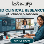 Hybrid Clinical Research Job at Johnson & Johnson Apply Now. A marketing banner promoting a "HYBRID CLINICAL RESEARCH JOB at Johnson & Johnson", featuring the Biotecnika logo. The central image shows a woman working at a desk, split between a laboratory environment (pipettes, vials) on the left and a home office (bookshelves, cat) on the right. She has dual monitors: one displaying research data, another showing a video conference call. Text on her desk nameplate says, "NAME - CLINICAL RESEARCHER at J&J". A large call-to-action button at the bottom reads "APPLY NOW".