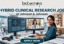 Hybrid Clinical Research Job at Johnson & Johnson Across India | Apply Now Hybrid Clinical Research Job at Johnson & Johnson Apply Now. A marketing banner promoting a "HYBRID CLINICAL RESEARCH JOB at Johnson & Johnson", featuring the Biotecnika logo. The central image shows a woman working at a desk, split between a laboratory environment (pipettes, vials) on the left and a home office (bookshelves, cat) on the right. She has dual monitors: one displaying research data, another showing a video conference call. Text on her desk nameplate says, "NAME - CLINICAL RESEARCHER at J&J". A large call-to-action button at the bottom reads "APPLY NOW".