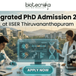 Integrated PhD Admission 2026 at IISER Thiruvananthapuram | Applications Invited Integrated PhD Admission 2026 at IISER Thiruvananthapuram. An inspiring featured image for Integrated PhD admission, featuring three students in lab coats collaborating in a modern IISER Thiruvananthapuram laboratory during golden hour. Large text at the top reads: "Integrated PhD Admission 2026 at IISER Thiruvananthapuram", with the Biotecnika logo. Below, students are pointing at a transparent screen with DNA structures and using a microscope, with a witty "Caffeine & CRISPR" mug. A large teal "APPLY NOW" button is at the bottom center.