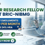 Junior Research Fellow Job at BRIC-NIBMG Apply Now. A promotional banner from Biotecnika for a Junior Research Fellow Job at BRIC-NIBMG. A central highlighted box states, "MONTHLY EMOLUMENTS: ₹37,000 PER MONTH PLUS 24% HRA" (indicated by small house icons). The banner features three benefits icons in green: "Advanced Research Facilities" with a microscope, "Genomics & Health" with a DNA helix, and "Career Mentorship" with a rising graph. A female scientist in a lab coat and safety glasses smiles while interacting with a futuristic holographic display showing intricate molecular structures and cellular data graphs. A prominent green button at the bottom says "APPLY NOW". The Biotecnika "Your Bio Resource" logo is prominent at the top left, and the website "www.biotecnika.org" is at the bottom right.