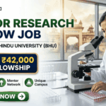 Junior Research Fellow Job at Banaras Hindu University Get ₹42,000 Fellowship. A corporate-style recruitment banner with a clean, attractive layout. At the top-left is the Biotecnika logo. The main text on the left reads 'JUNIOR RESEARCH FELLOW JOB' in large, bold dark green and blue text, with 'AT BANARAS HINDU UNIVERSITY (BHU)' below it. A prominent gold-framed graphic features a money bag with a rupee symbol and a stack of rupee bills, with large gold text above reading 'GET ₹42,000' and blue text below: 'FELLOWSHIP'. To the right, a young female researcher in a lab coat and safety glasses is seated at a lab bench, intently looking through a microscope at a multi-well plate. Below the main text on the left, three circular green icons describe benefits: a microscope for 'Advanced Projects', two figures with a mortarboard for 'Mentor Network', and a rising star-arrow for 'Unique Campus'. A large, rounded green 'APPLY NOW' button with a white right-pointing arrow is centered at the bottom. The overall design is corporate, realistic, and highly attractive.