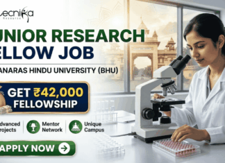 Junior Research Fellow Job at Banaras Hindu University | Get ₹42,000 Fellowship Junior Research Fellow Job at Banaras Hindu University Get ₹42,000 Fellowship. A corporate-style recruitment banner with a clean, attractive layout. At the top-left is the Biotecnika logo. The main text on the left reads 'JUNIOR RESEARCH FELLOW JOB' in large, bold dark green and blue text, with 'AT BANARAS HINDU UNIVERSITY (BHU)' below it. A prominent gold-framed graphic features a money bag with a rupee symbol and a stack of rupee bills, with large gold text above reading 'GET ₹42,000' and blue text below: 'FELLOWSHIP'. To the right, a young female researcher in a lab coat and safety glasses is seated at a lab bench, intently looking through a microscope at a multi-well plate. Below the main text on the left, three circular green icons describe benefits: a microscope for 'Advanced Projects', two figures with a mortarboard for 'Mentor Network', and a rising star-arrow for 'Unique Campus'. A large, rounded green 'APPLY NOW' button with a white right-pointing arrow is centered at the bottom. The overall design is corporate, realistic, and highly attractive.