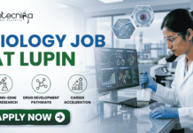 Latest Biology Job At Lupin | BSc Candidates Apply Before It’s Gone! Latest Biology Job At Lupin BSc Candidates Apply Before It's Gone! A detailed, professional recruitment banner for a "BIOLOGY JOB AT LUPIN" by biotecnika Your Bio Resource. The banner features a focused female Indian scientist in a lab coat and safety glasses, using a multichannel pipette to fill a microplate in a modern laboratory. Overlaid on the background, which includes a campus view and scientific monitors with bio-prospecting data and molecular models, are hexagonal panels displaying a DNA helix, a cell structure, and a plant sample. Three key career benefits are listed with icons in green circles: "CUTTING-EDGE DRUG RESEARCH", "DRUG DEVELOPMENT PATHWAYS", and "CAREER ACCELERATION". A prominent green "APPLY NOW" button with a white right arrow is at the bottom center. The company logo is at the top left, and the job title text is prominent on the left.