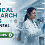 Latest Clinical Research Jobs at Amneal Apply Before It Closes! A professional corporate recruitment banner for "CLINICAL RESEARCH JOBS AT AMNEAL" featuring the Biotecnika logo. The image showcases a focused female scientist of Indian heritage in a white lab coat and safety goggles, interacting with a high-tech digital monitor displaying clinical trial data and ECG waveforms. To the right, hexagonal icons highlight key clinical research themes: "Continuous Patient Monitoring," "Multi-modal Data Integration," and "Accelerated Study Timelines." The background depicts a modern, brightly lit clinical facility with other researchers at work. A prominent green "APPLY NOW" button with a white arrow is positioned at the bottom left.