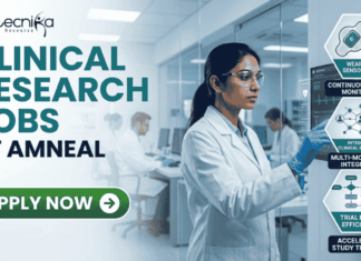 Latest Clinical Research Jobs at Amneal | Apply Before It Closes! Latest Clinical Research Jobs at Amneal Apply Before It Closes! A professional corporate recruitment banner for "CLINICAL RESEARCH JOBS AT AMNEAL" featuring the Biotecnika logo. The image showcases a focused female scientist of Indian heritage in a white lab coat and safety goggles, interacting with a high-tech digital monitor displaying clinical trial data and ECG waveforms. To the right, hexagonal icons highlight key clinical research themes: "Continuous Patient Monitoring," "Multi-modal Data Integration," and "Accelerated Study Timelines." The background depicts a modern, brightly lit clinical facility with other researchers at work. A prominent green "APPLY NOW" button with a white arrow is positioned at the bottom left.