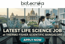 Latest Life Science Job at Thermo Fisher Scientific Bangalore | Apply Online Here Latest Life Science Job at Thermo Fisher Scientific Bangalore Apply Online Here. An attractive job advertisement banner from Biotecnika, featuring three scientists in white lab coats actively working in a modern laboratory. In the background, visible through a large window, is the recognizable Vidhana Soudha building in Bengaluru. Prominent text overlay reads: "LATEST LIFE SCIENCE JOB at THERMO FISHER SCIENTIFIC BANGALORE". At the top is the Biotecnika logo, and at the bottom center is a "APPLY NOW" button. A "NEW OPENING" handshake badge is in the top right.