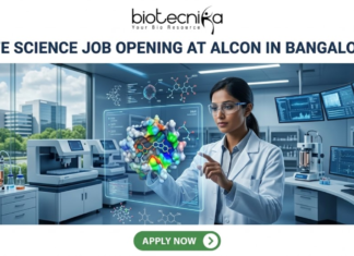 Life Science Job Opening at Alcon in Bangalore | Apply Before It’s Gone Life Science Job Opening at Alcon in Bangalore. A corporate job advertisement banner for a Life Science Job Opening at Alcon in Bangalore. The image features a female scientist of South Asian descent in a high-tech laboratory, interacting with a glowing holographic 3D protein-drug molecular model. The background shows advanced lab equipment, data monitors, and a view of modern Bangalore buildings through a large window. The Biotecnika logo is at the top center, the headline is in bold dark text, and a green 'Apply Now' button is located at the bottom.