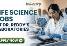 Life Science Jobs at Dr. Reddy’s Laboratories | BSc & MSc Candidates Apply Now! Life Science Jobs at Dr. Reddy's Laboratories BSc & MSc Candidates Apply Now! A professional corporate recruitment banner for "LIFE SCIENCE JOBS AT DR. REDDY'S LABORATORIES" featuring the Biotecnika logo at the top. The image depicts a focused female scientist of Indian heritage wearing a white lab coat, safety goggles, and blue gloves, working with a modern automated liquid handling system and microplates. Hexagonal graphics to the right showcase scientific concepts like a DNA helix labeled 'CRISPR', a microfluidic chip, and a biological cell. In the background, a team of researchers is visible in a clean, state-of-the-art laboratory environment. A prominent green "APPLY NOW" button with a white arrow is located at the bottom left.