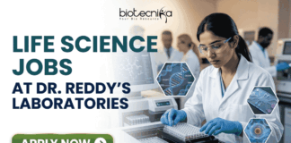 Life Science Jobs at Dr. Reddy’s Laboratories | BSc & MSc Candidates Apply Now! Life Science Jobs at Dr. Reddy's Laboratories BSc & MSc Candidates Apply Now! A professional corporate recruitment banner for "LIFE SCIENCE JOBS AT DR. REDDY'S LABORATORIES" featuring the Biotecnika logo at the top. The image depicts a focused female scientist of Indian heritage wearing a white lab coat, safety goggles, and blue gloves, working with a modern automated liquid handling system and microplates. Hexagonal graphics to the right showcase scientific concepts like a DNA helix labeled 'CRISPR', a microfluidic chip, and a biological cell. In the background, a team of researchers is visible in a clean, state-of-the-art laboratory environment. A prominent green "APPLY NOW" button with a white arrow is located at the bottom left.