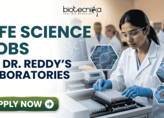 Life Science Jobs at Dr. Reddy’s Laboratories | BSc & MSc Candidates Apply Now! Life Science Jobs at Dr. Reddy's Laboratories BSc & MSc Candidates Apply Now! A professional corporate recruitment banner for "LIFE SCIENCE JOBS AT DR. REDDY'S LABORATORIES" featuring the Biotecnika logo at the top. The image depicts a focused female scientist of Indian heritage wearing a white lab coat, safety goggles, and blue gloves, working with a modern automated liquid handling system and microplates. Hexagonal graphics to the right showcase scientific concepts like a DNA helix labeled 'CRISPR', a microfluidic chip, and a biological cell. In the background, a team of researchers is visible in a clean, state-of-the-art laboratory environment. A prominent green "APPLY NOW" button with a white arrow is located at the bottom left.