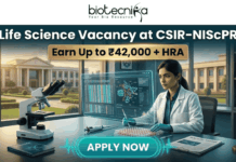 Latest Life Science Vacancy at CSIR-NIScPR | MSc Candidates Earn Upto ₹42,000/- Life Science Vacancy at CSIR-NIScPR Earn Up to ₹42,000 + HRA. A promotional job advertisement banner for a "Life Science Vacancy at CSIR-NIScPR." The central image features a female researcher in a lab coat and gloves at a sophisticated laboratory desk. She is using a micropipette with a futuristic, transparent data display. Foreground objects include a microscope, a multi-well plate, stacks of scientific journals, and a DNA helix model. Behind her are large windows showing a grand, classical-style campus building under a sunny sky, representing the institute. At the top center, the Biotecnika "Your Bio Resource" logo is visible. The text reads: "Life Science Vacancy at CSIR-NIScPR", with a prominent gold banner below highlighting: "Earn Up to ₹42,000 + HRA". A large, pulsing teal button at the bottom center says "APPLY NOW."