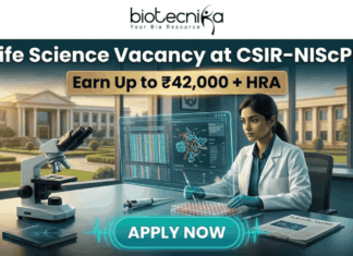 Latest Life Science Vacancy at CSIR-NIScPR | MSc Candidates Earn Upto ₹42,000/- Life Science Vacancy at CSIR-NIScPR Earn Up to ₹42,000 + HRA. A promotional job advertisement banner for a "Life Science Vacancy at CSIR-NIScPR." The central image features a female researcher in a lab coat and gloves at a sophisticated laboratory desk. She is using a micropipette with a futuristic, transparent data display. Foreground objects include a microscope, a multi-well plate, stacks of scientific journals, and a DNA helix model. Behind her are large windows showing a grand, classical-style campus building under a sunny sky, representing the institute. At the top center, the Biotecnika "Your Bio Resource" logo is visible. The text reads: "Life Science Vacancy at CSIR-NIScPR", with a prominent gold banner below highlighting: "Earn Up to ₹42,000 + HRA". A large, pulsing teal button at the bottom center says "APPLY NOW."