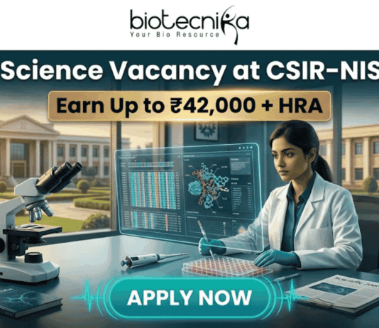 Latest Life Science Vacancy at CSIR-NIScPR | MSc Candidates Earn Upto ₹42,000/- Life Science Vacancy at CSIR-NIScPR Earn Up to ₹42,000 + HRA. A promotional job advertisement banner for a "Life Science Vacancy at CSIR-NIScPR." The central image features a female researcher in a lab coat and gloves at a sophisticated laboratory desk. She is using a micropipette with a futuristic, transparent data display. Foreground objects include a microscope, a multi-well plate, stacks of scientific journals, and a DNA helix model. Behind her are large windows showing a grand, classical-style campus building under a sunny sky, representing the institute. At the top center, the Biotecnika "Your Bio Resource" logo is visible. The text reads: "Life Science Vacancy at CSIR-NIScPR", with a prominent gold banner below highlighting: "Earn Up to ₹42,000 + HRA". A large, pulsing teal button at the bottom center says "APPLY NOW."