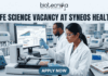 Life Science Vacancy at Syneos Health | BSc Candidates Apply Now Life Science Vacancy at Syneos Health BSc Candidates Apply Now. A complete job advertisement featured image banner. At the very top center, it features the full Biotecnika logo and tagline ("biotecnika", abstract human-leaf figure, "Your Bio Resource"). Directly below, a large text headline reads: "LIFE SCIENCE VACANCY AT SYNEOS HEALTH". The main scene is a photograph of a modern, well-equipped laboratory with two focused researchers. A female researcher in the foreground is actively pipetting over microtiter plates. Behind her, her male colleague works at a large computer station. The monitor screen is clearly legible and displays complex "PHASE III TRIAL TRACKING" data, graphs, and clinical recruitment charts. Advanced lab equipment like an automated liquid handling system and color-coded samples are on the bench, alongside a lab notebook with molecular doodles. At the bottom center, a prominent deep teal-blue button with bold white text displays "APPLY NOW".