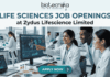 Life Sciences Job Openings at Zydus Lifescience Limited | Walk-In Interview 2026 Life Sciences Job Openings at Zydus Lifescience Limited Walk-In Interview 2026. A promotional banner from Biotecnika, titled 'LIFE SCIENCES JOB OPENINGS at Zydus Lifescience Limited'. The image features a photo of three diverse and collaborative researchers in a modern laboratory. One woman in a lab coat is smiling and pointing to a computer monitor displaying 'SUCCESSFUL PHASE III RESULTS' and scientific data visualizations. Her colleagues look on with interest. Laboratory tools like pipettes, petri dishes with samples, vials, and a laptop are visible on the desk. At the bottom center, a prominent blue button reads 'APPLY NOW' with an arrow icon. The overall theme is successful, modern scientific collaboration.