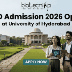 PhD Admission 2026 Open at University of Hyderabad | Research Career Opportunity PhD Admission 2026 Open at University of Hyderabad. An advertisement for PhD Admission 2026 at the University of Hyderabad. The image features a photo of the university campus with three smiling people walking on a pathway, one holding a tablet showing a molecular diagram and another holding a book titled 'Advanced Research'. The biotecnika logo is at the top center. The main headline is 'PhD Admission 2026 Open at University of Hyderabad'. There is a green 'APPLY NOW' button with subtext providing a website and application deadline: 'Visit www.biotecnika.org for application details. Application Deadline: October 2025'.