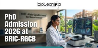 PhD Admission 2026 at BRIC-RGCB Unlock Your Life Science Career Dream! Promotional banner for Biotecnika, "Your Bio Resource," advertising PhD Admission 2026 at BRIC-RGCB (Rajiv Gandhi Centre for Biotechnology). The central image is of a female scientist in safety glasses and a lab coat working with advanced lab equipment and a large computer monitor displaying DNA and protein visualizations. In the background, a sign on a glass partition reads "BRIC - Rajiv Gandhi Centre for Biotechnology," and a modern research campus is visible through windows. At the bottom, a prominent green button with white text says "APPLY NOW."