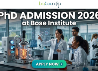 PhD Admission 2026 at Bose Institute | Dream Opportunity for Life Science Candidates in India! PhD Admission 2026 at Bose Institute Life Science Opportunity. A professional and high-tech featured image for the Project Research Scientist Recruitment 2026 at ICMR-NIN. The image depicts a female scientist in a white lab coat interacting with a glowing, transparent digital interface that displays complex nutritional genomics data, 3D DNA structures, and metabolic charts. The background shows a modern, sunlit laboratory with a city skyline visible through the window. The Biotecnika logo is featured at the top center, and a prominent teal "Apply Now" button is positioned at the bottom.