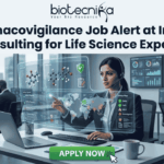 Pharmacovigilance Job Alert at Infosys Consulting for Life Science Experts! Pharmacovigilance Job Alert at Infosys Consulting for Life Science Experts! A job advertisement graphic with text at the top that reads: "biotecnika" and "Your Bio Resource" with a stylized icon, followed by the headline, "Pharmacovigilance Job Alert at Infosys Consulting for Life Science Experts!". The central image shows a woman of South Asian descent wearing a headset, seated at a desk with a laptop in a modern office setting. She is looking at and reaching toward a futuristic, transparent data display interface with molecular structures, a world map, data charts, and labels like "Safety Reports," "Product Reports," and a "Safety Map" legend indicating colored zones for alert, warning, and safety. Other employees are working at desks in the background of a glass-walled high-rise office. At the bottom center, there is a large green button with white text that reads "APPLY NOW", and a hand cursor is clicking it.