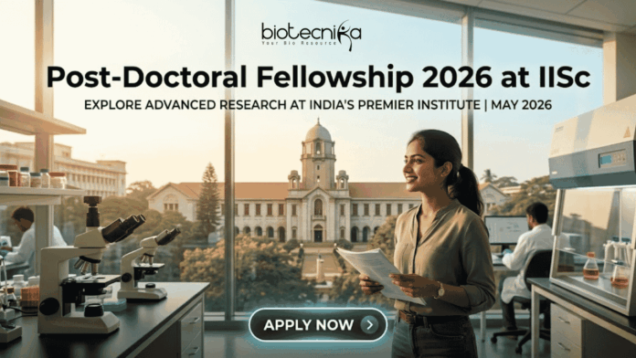 Post-Doctoral Fellowship At IISc Bengaluru Earn ₹2 Lakh Grant Post-Doctoral Fellowship At IISc Bengaluru Earn ₹2 Lakh Grant. An attractive and realistic featured image for a job page from biotecnika. At the top, the biotecnika logo is centered. Large, bold centered text below reads, "Post-Doctoral Fellowship 2026 at IISc," with a smaller sub-headline that says, "EXPLORE ADVANCED RESEARCH AT INDIA'S PREMIER INSTITUTE | MAY 2026." The image features a female Indian researcher smiling in a modern laboratory, holding documents. Various lab equipment like microscopes and other scientists in the background are visible. Through the large windows, a recognizable, grand academic building and trees are visible, implying the IISc campus under a warm, golden light. At the bottom center, a rounded button reads "APPLY NOW >." The image is relatable, attention-grabbing, and unique.