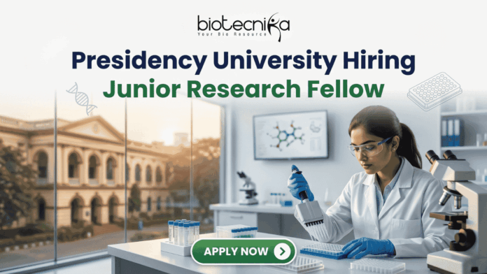 Presidency University Hiring Junior Research Fellow Earn Upto ₹25,000 Salary! Presidency University Hiring Junior Research Fellow Earn Upto ₹25,000 Salary! A recruitment banner for Presidency University featuring the text 'Presidency University Hiring Junior Research Fellow' at the top, along with the 'biotecnika' logo. On the left side, the iconic colonial architecture of Presidency University's building is visible through a window, with a view of the sun setting. The right side features a female Indian scientist of a professional and focused appearance, wearing a lab coat, safety glasses, and blue gloves, meticulously using a pipette to fill a well-plate. She is surrounded by modern laboratory equipment, including a microscope and a monitor displaying molecular structures. Floating icons of DNA double helices are subtly placed around the text area. An 'APPLY NOW' button is prominent at the bottom center.