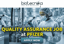 Quality Assurance Job at Pfizer | BSc & MSc Biotech Candidates Apply Now Quality Assurance Job at Pfizer BSc & MSc Biotech Candidates Apply Now. A promotional job banner with the Biotecnika logo at the top. Large yellow and white text reads: 'QUALITY ASSURANCE JOB at PFIZER'. The background is a photograph of a person in a full cleanroom suit and goggles, scanning equipment in a state-of-the-art pharmaceutical manufacturing lab. A turquoise 'APPLY NOW' button is at the bottom.
