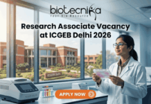 Research Associate Vacancy at ICGEB Delhi 2026 | PhD Candidates Apply Now Research Associate Vacancy at ICGEB Delhi 2026 PhD Candidates Apply Now. A promotional banner image for a job opening. The top center features the text logo "biotecnika - Your Bio Resource." Below it, a large headline reads "Research Associate Vacancy at ICGEB Delhi 2026." On the right, a female scientist in a white lab coat and glasses holds a well plate with colored samples, looking up at it. The setting is a modern biotechnology lab. On the counter on the left, there is lab equipment, including a piece labeled "ICGEB DELHI." Through a large window in the background, a red-brick university campus is visible, with a sign reading "ICGEB Delhi." An orange-red call-to-action button at the bottom center says "APPLY NOW" with a right arrow icon.