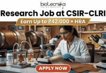 Research Job at CSIR-CLRI | Earn Up to ₹42,000 + HRA | Apply Before Deadline Research Job at CSIR-CLRI Earn Up to ₹42,000 + HRA. A promotional banner advertisement from Biotecnika, titled "Research Job at CSIR-CLRI", featuring a prominent gold banner with text that reads: "Earn Up to ₹42,000 + HRA". The main image shows a female scientist in a lab coat, safety glasses, and blue gloves, using a stereo microscope to analyze a textured material sample (likely a leather sample, given CLRI's focus). She is at a laboratory bench equipped with other microscopes, glass apparatus with samples, chemical bottles, and a computer monitor showing data. In the background are larger industrial lab machines. The Biotecnika "Your Bio Resource" logo is at the top center. At the bottom, a red button with white text reads: "APPLY NOW".