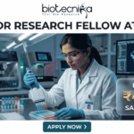 Research Jobs Alert: Gujarat Biotechnology University JRF Recruitment 2026 – Earn ₹47,000/Month Research Job at Gujarat Biotechnology University with ₹47,000 Pay. A job advertisement banner featuring the Biotecnika logo and the headline 'JUNIOR RESEARCH FELLOW AT GBU'. The visual depicts a female scientist in a modern lab using a multi-channel pipette, surrounded by scientific equipment and a computer monitor showing a molecular structure. A prominent side panel highlights the salary as 'EARN UPTO ₹47,000 SALARY/MONTH'. At the bottom, a teal button says 'APPLY NOW >'.