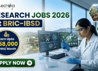 Research Jobs at BRIC-IBSD | Walk-In Interview for Life Science Candidates Research Jobs at BRIC-IBSD Walk-In Interview for Life Science Candidates. A professional recruitment banner for biotecnika advertising "Research Jobs 2026 at BRIC-IBSD." The top left features the biotecnika logo, and the headline text is prominent in blue and green. A circular blue callout on the left highlights the compensation: "Earn Upto ₹58,000 + HRA/ Month." On the right, a focused female scientist of professional and realistic appearance, wearing a white lab coat and safety glasses, is seated at a modern lab desk, using a pipette to fill a microplate. In the background, computer monitors display complex data including molecular structures and "Bioresource mapping" on a world map. Through a large window, a scenic modern building, perhaps the BRIC-IBSD institute, is visible in a lush environment. Two hexagonal icons on the far right show a network diagram over fresh produce and a sustainability tree icon. A prominent green "APPLY NOW" button with an arrow is at the bottom left.