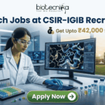Exciting Research Jobs at CSIR-IGIB | Get Upto ₹42,000 Salary/ Month Research Jobs at CSIR-IGIB Recruitment Get Upto ₹42,000 Salary Month. A promotional banner for research jobs at CSIR-IGIB. At the top, the Biotecnika logo and the headline "Research Jobs at CSIR-IGIB Recruitment" are shown. Below, the salary details "Get Upto ₹42,000 Salary/ Month" are highlighted. The central image shows a female scientist in a lab working with a pipette, next to a monitor displaying a 3D molecular protein structure. Through a window, a modern CSIR-IGIB campus building is visible. A green "Apply Now" button is at the bottom.