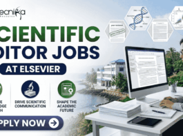 Scientific Editor Jobs at Elsevier | PhD Candidates Apply Now! Scientific Editor Jobs at Elsevier | PhD Candidates Apply Now! A professional featured image for "Scientific Editor Jobs at Elsevier" featuring the Biotecnika logo at the top left. On the right, a woman in a grey business blazer is seated at a desk, focused on a computer screen showing an edited research manuscript. The left side displays the bold headline "SCIENTIFIC EDITOR JOBS AT ELSEVIER" along with three icons representing research evaluation, scientific communication, and shaping the academic future. The background includes floating scientific diagrams and a scenic coastal building view, with a prominent "Apply Now" button at the bottom.