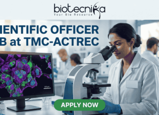 Scientific Officer Job at TMC-ACTREC | Earn Upto ₹40,000 Salary Scientific Officer Job at TMC-ACTREC. A job advertisement banner from biotecnika. At the top, the "biotecnika Your Bio Resource" logo with a stylized figure is displayed above the text 'SCIENTIFIC OFFICER JOB at TMC-ACTREC'. The main image shows a female scientist of South Asian appearance in a lab coat, looking through a complex multi-headed microscope. To her left, a computer monitor displays a vibrant, multi-colored confocal micrograph of stained cells with a scale bar, showcasing high-resolution cell imaging. Other researchers are working at distant lab benches in the background. Below the monitor, a text line reads, 'Explore groundbreaking oncology research in a world-class institute.' At the bottom center is a green 'APPLY NOW' button. The overall setting is a modern biological laboratory with various glass labware and equipment.