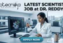 Latest Scientist Job at Dr. Reddy’s | MSc Food Science Job Opportunity Scientist Job at Dr. Reddy’s MSc Food Science Job. A detailed job advertisement image for a scientist position. At the top-left is the biotecnika logo 'biotecnika Your Bio Resource'. Large headline text to the top-right reads: 'LATEST SCIENTIST JOB at DR. REDDY'S'. The central scene features a focused female scientist, 'Dr. A. Rao, R&D Lead', in a modern, high-tech pharmaceutical research laboratory. She is working at a computer station, using a multi-channel pipette on a multi-well plate. Her monitor displays complex 3D molecular visualizations of protein structures, with text labels like 'KINASE TARGET LEAD OPTIMIZATION' and 'CONFIRMATION OF BINDING SUCCESSFUL'. The extensive lab background shows automated equipment, analytical tools, and a view of a modern city from a window. A coffee mug and a sticky note reading 'Potential breakthrough kinase data' are on the desk. A prominent blue 'APPLY NOW' button is at the bottom center.