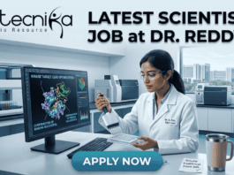 Scientist Job at Dr. Reddy’s MSc Food Science Job. A detailed job advertisement image for a scientist position. At the top-left is the biotecnika logo 'biotecnika Your Bio Resource'. Large headline text to the top-right reads: 'LATEST SCIENTIST JOB at DR. REDDY'S'. The central scene features a focused female scientist, 'Dr. A. Rao, R&D Lead', in a modern, high-tech pharmaceutical research laboratory. She is working at a computer station, using a multi-channel pipette on a multi-well plate. Her monitor displays complex 3D molecular visualizations of protein structures, with text labels like 'KINASE TARGET LEAD OPTIMIZATION' and 'CONFIRMATION OF BINDING SUCCESSFUL'. The extensive lab background shows automated equipment, analytical tools, and a view of a modern city from a window. A coffee mug and a sticky note reading 'Potential breakthrough kinase data' are on the desk. A prominent blue 'APPLY NOW' button is at the bottom center.