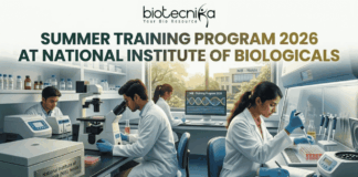 Summer Training Program 2026 at National Institute of Biologicals. A promotional graphic for the "SUMMER TRAINING PROGRAM 2026 AT NATIONAL INSTITUTE OF BIOLOGICALS", presented by biotecnika. Text at the top is green. The main image shows a diverse group of scientists and trainees working in a well-equipped laboratory. A central woman scientist is focused on a microscope, a male scientist works with liquid samples, and other figures are in the background. Equipment includes computer monitors with DNA graphics, test tubes, and a centrifuge labeled "National Institute of Biologicals (NIB), Noida". A large orange "APPLY NOW" button is at the bottom.
