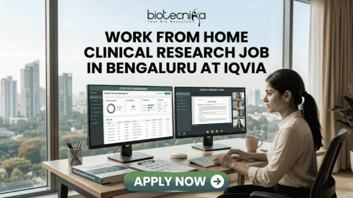 Work From Home Clinical Research Job in Bengaluru at IQVIA Work From Home Clinical Research Job in Bengaluru at IQVIA. A professional job advertisement banner for a "Work From Home Clinical Research Job in Bengaluru at IQVIA." The image features the Biotecnika logo at the top and a central headline in bold text. Below the text, a woman is shown working at a modern desk with a scenic city skyline view in the background. She is using a dual-monitor setup displaying clinical trial data management software and a video conference with a research team. A prominent green "Apply Now" button with a white arrow is located at the bottom center.
