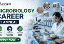 Amneal Microbiology Job 2026 – M.Sc Microbiology Candidates Can Apply Now Amneal Microbiology Job 2026 – M.Sc Microbiology Candidates Can Apply Now. A professional promotional banner for a "Microbiology Career at Amneal," featuring the Biotecnika logo at the top left. On the right, a female scientist in a white lab coat is working in a high-tech microbiology laboratory, examining colorful petri dishes with an inoculation loop. The left side features the bold headline "MICROBIOLOGY CAREER AT AMNEAL" and three icons representing: Monitor Product Safety, Conduct Microbial Analyses, and Advance QA/QC & R&D. The background includes hexagonal floating graphics showing various bacterial cultures and laboratory autoclaves. A prominent green "Apply Now" button with a white arrow is located at the bottom left.