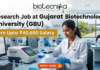 ₹40,600 Salary Research Job at Gujarat Biotechnology University (GBU) | JRF & SRF Openings ₹40,600 Salary Research Job at Gujarat Biotechnology University (GBU) JRF & SRF Openings. A focused female researcher in a white lab coat uses a multi-channel pipette on a microplate within a modern GBU laboratory. Large bold text reads: 'Research Job at Gujarat Biotechnology University (GBU)'. A yellow banner highlights 'Earn Upto ₹40,600 Salary'. The Biotecnika logo is at the top. The background features GBU lab equipment, a monitor with DNA graphs, another researcher, and GBU campus views. At the bottom center is an orange 'APPLY NOW' button with a right arrow.